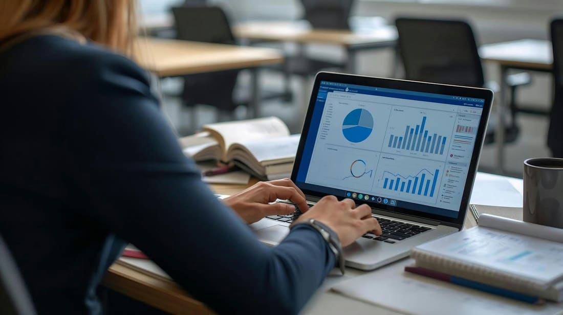Someone working at a laptop showing a dashboard of financial charts
